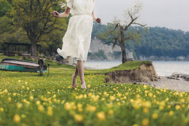 Frau im weißen Kleid geht auf Gras - OMIF00991