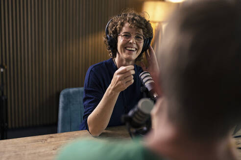 Fröhliche Moderatorin mit Brille im Gespräch mit einem Gast in einer Radiostation - JOSEF11141