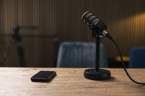 Smart phone by microphone on desk in recording studio - JOSEF11149