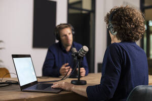 Presenter wearing headset interviewing guest in recording studio - JOSEF11156