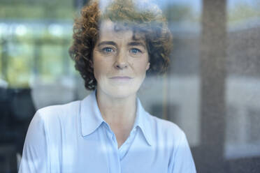 Businesswoman with curly hair seen through glass - JOSEF11177