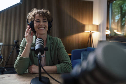 Glücklicher Moderator mit Headset, der einen Podcast in einer Radiostation aufnimmt - JOSEF11202