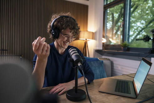 Zufriedener Moderator, der über ein Mikrofon in einer Radiostation aufnimmt - JOSEF11218