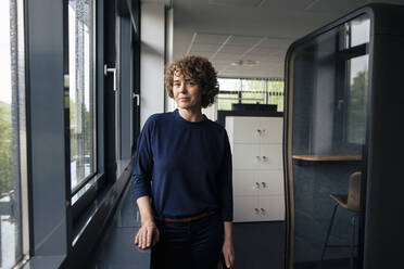 Businesswoman standing by window in office - JOSEF11224