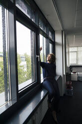 Glückliche Geschäftsfrau, die ein Selfie mit ihrem Smartphone auf der Fensterbank macht - JOSEF11226