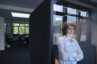 Businesswoman standing with arms crossed in soundproof cabin - JOSEF11244