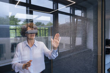 Geschäftsfrau im Virtual-Reality-Simulator gestikuliert durch Glas gesehen - JOSEF11256
