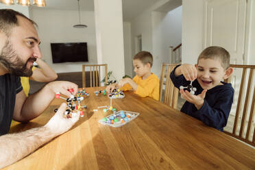 Happy boy holding molecular model by father at home - OSF00427