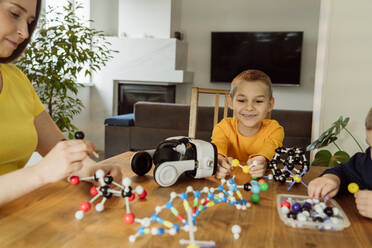 Smiling boy looking at DNA model on table - OSF00430