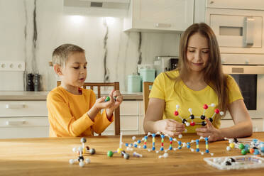 Mutter und Sohn halten Moleküle auf dem Tisch zu Hause - OSF00434