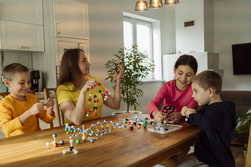Mutter und Kinder mit Molekularstrukturen auf dem Tisch zu Hause - OSF00435
