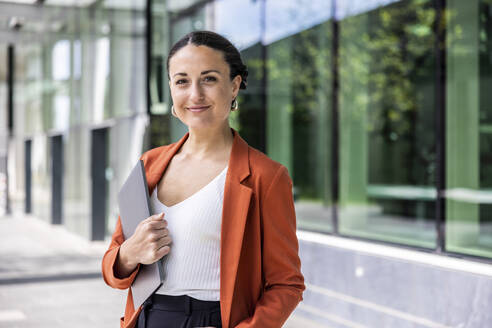 Smiling businesswoman holding laptop - WPEF06200