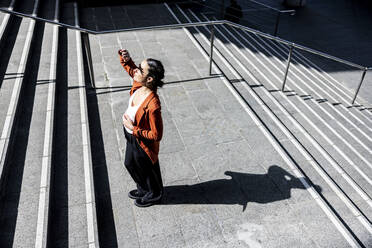 Businesswoman shielding eyes from sunlight on staircase - WPEF06218
