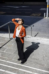 Businesswoman shielding eyes standing on staircase - WPEF06219