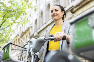 Smiling businesswoman with electric bicycle - WPEF06235