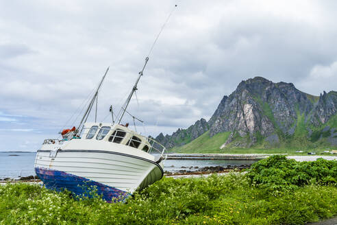 Norwegen, Nordland, Fischerboot an der Küste der Insel Andoya mit hohen Klippen im Hintergrund - STSF03328