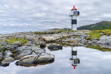 Norwegen, Nordland, Leuchtturm mit Spiegelung im Küstenwasser - STSF03332