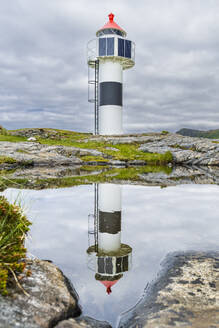 Norwegen, Nordland, Leuchtturm mit Spiegelung im Küstenwasser - STSF03333