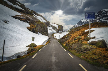 Norway, Rogaland, Sauda, Road 520 stretching between snow-covered hills - RJF00910