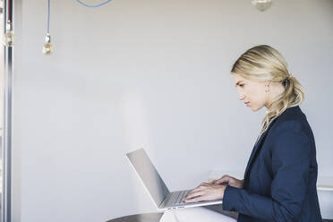 Blonde Geschäftsfrau mit Laptop im Büro - UUF26920