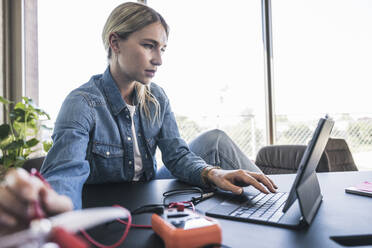 Frau programmiert Drohne mit Tablet-PC am Schreibtisch im Büro - UUF26949