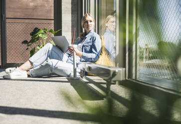 Geschäftsfrau mit Tablet-PC und Windradmodell im Büro an einem sonnigen Tag - UUF26955