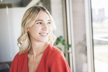 Happy young businesswoman with blond hair in office - UUF26961