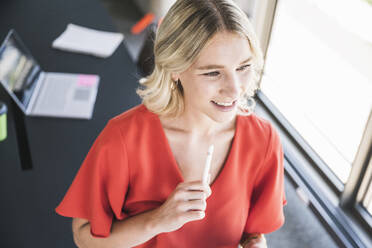Lächelnde Geschäftsfrau mit digitalisiertem Stift im Büro - UUF26969
