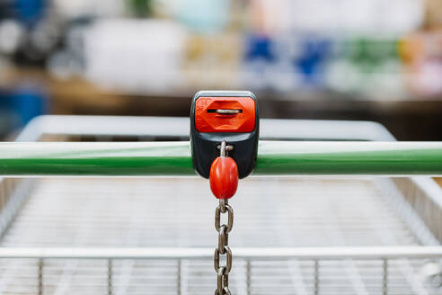 Shopping trolley with coin lock attached to chair on blurred background of store - ADSF36019