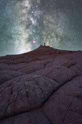 Silhouette eines nicht erkennbaren Forschers, der auf einer Kulisse von Felsformationen im Hochland unter einem milchigen Sternenhimmel im Vermillion Cliffs National Monument, Arizona in den USA steht - ADSF36059