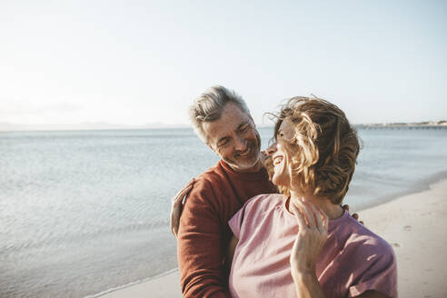 Glückliche blonde Frau mit Mann, die ihren Urlaub am Strand genießen - JOSEF11303