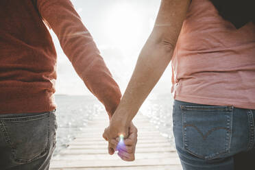Couple holding hands at beach on sunny day - JOSEF11328