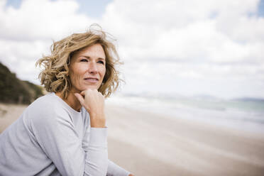 Mature woman with hand on chin at beach - JOSEF11341