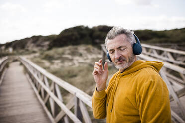 Älterer Mann mit geschlossenen Augen hört Musik über drahtlose Kopfhörer - JOSEF11350