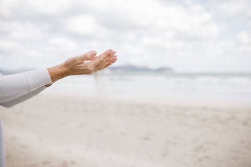 Die Hände einer reifen Frau halten Sand am Strand - JOSEF11354