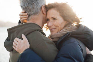 Happy mature woman hugging man on sunny day - JOSEF11380