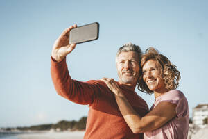 Lächelnder Mann nimmt Selfie mit Frau durch Smartphone - JOSEF11386