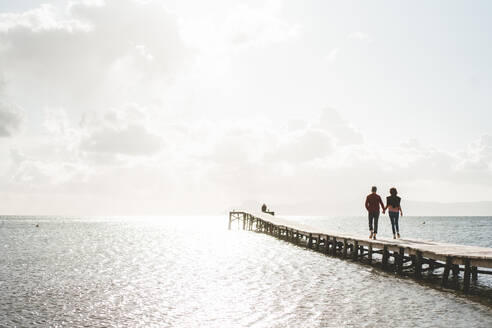 Älteres Paar, das sich an den Händen hält, geht auf einem Steg über das Meer - JOSEF11391