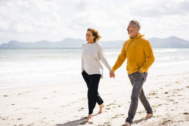 Happy couple holding hands walking at shore on sunny day - JOSEF11412