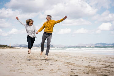 Fröhliches reifes Paar, das seinen Urlaub am Strand genießt - JOSEF11417