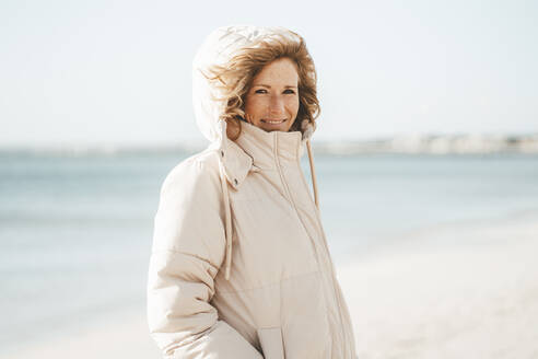 Smiling mature woman standing at beach - JOSEF11437