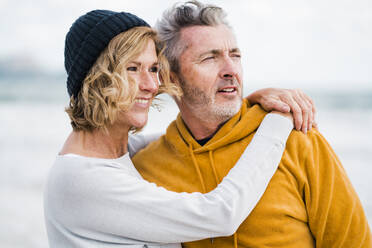 Happy woman with arm around man at beach - JOSEF11470