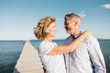 Smiling woman with man standing at jetty on sunny day - JOSEF11485