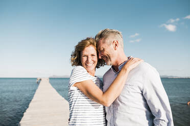 Loving man embracing woman on jetty at vacation - JOSEF11489