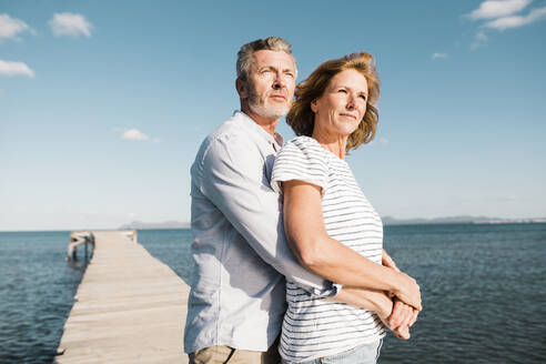 Smiling woman with man standing on jetty at beach - JOSEF11499