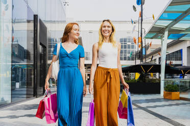 Lächelnde Frauen mit Einkaufstaschen vor einem Einkaufszentrum - OIPF02073