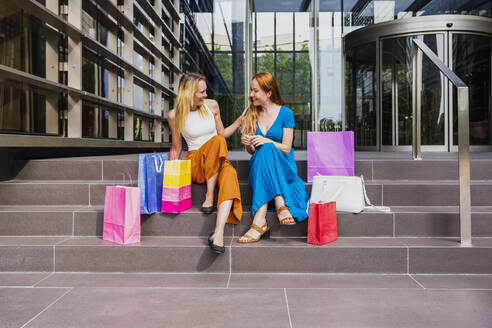 Frauen mit Einkaufstaschen sitzen auf den Stufen vor dem Einkaufszentrum - OIPF02076
