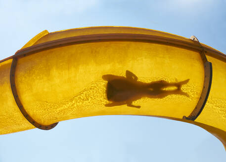 Silhouette of two people sliding down water slide - BSCF00663