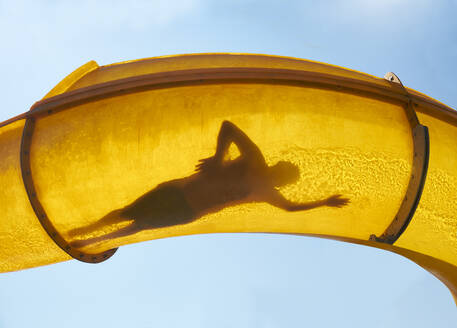 Silhouette of person sliding down water slide - BSCF00664