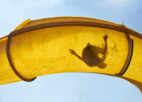 Silhouette of person sliding down water slide - BSCF00665